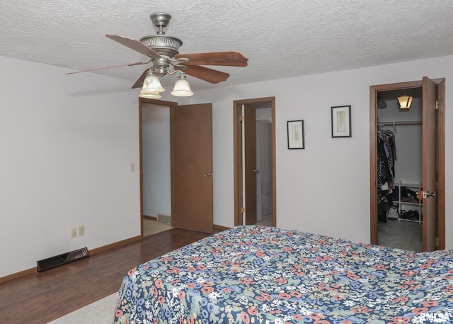 bedroom with dark wood-type flooring, a closet, a spacious closet, and a textured ceiling