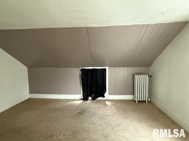 bonus room with vaulted ceiling, radiator heating unit, and light colored carpet