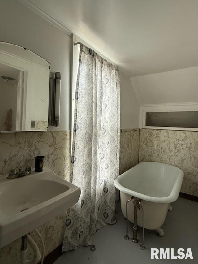 bathroom featuring vaulted ceiling, sink, a bathtub, and concrete floors