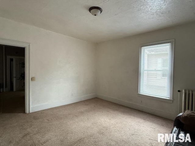 empty room with carpet, plenty of natural light, radiator, and a textured ceiling