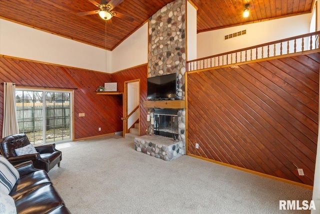 carpeted living room featuring a stone fireplace, high vaulted ceiling, wooden ceiling, and wooden walls