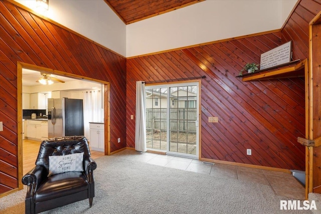 sitting room featuring light colored carpet, high vaulted ceiling, and wood walls