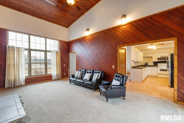 carpeted living room featuring ceiling fan, wooden ceiling, high vaulted ceiling, and wood walls