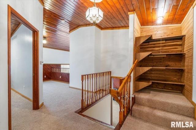 stairs featuring crown molding, carpet flooring, wood ceiling, and wood walls