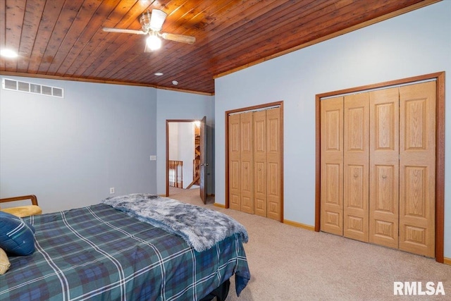 carpeted bedroom featuring crown molding, wood ceiling, two closets, and ceiling fan