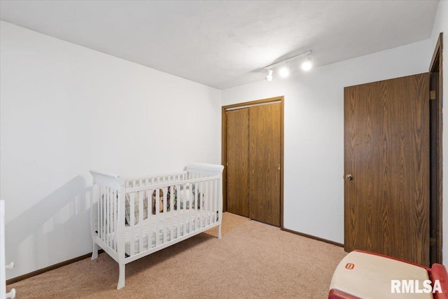 bedroom featuring light colored carpet, track lighting, and a closet