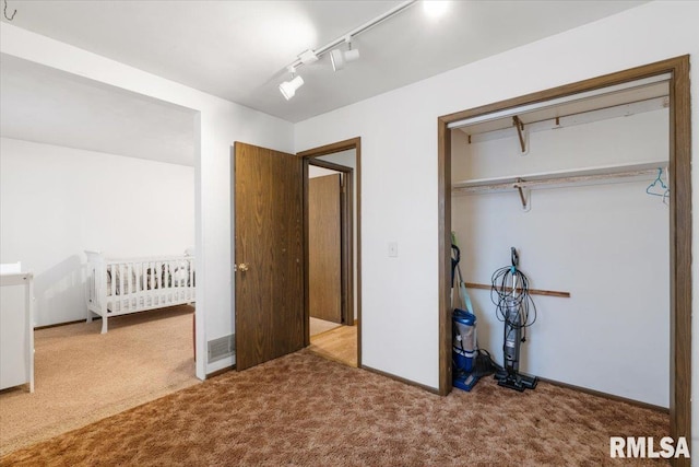 unfurnished bedroom featuring carpet, track lighting, and a closet