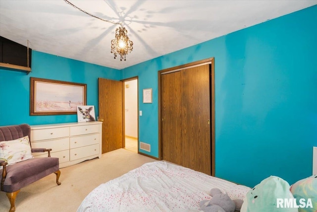 carpeted bedroom featuring an inviting chandelier and a closet