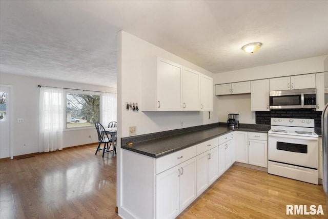 kitchen featuring white cabinets, light wood-type flooring, and electric range