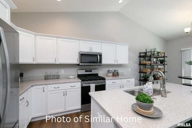 kitchen featuring vaulted ceiling, sink, white cabinets, light stone counters, and stainless steel appliances