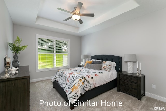 carpeted bedroom featuring ceiling fan and a tray ceiling