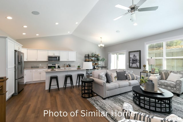 living room with lofted ceiling, ceiling fan with notable chandelier, and dark hardwood / wood-style flooring