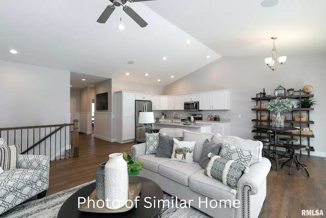 living room featuring lofted ceiling, sink, ceiling fan with notable chandelier, and dark wood-type flooring