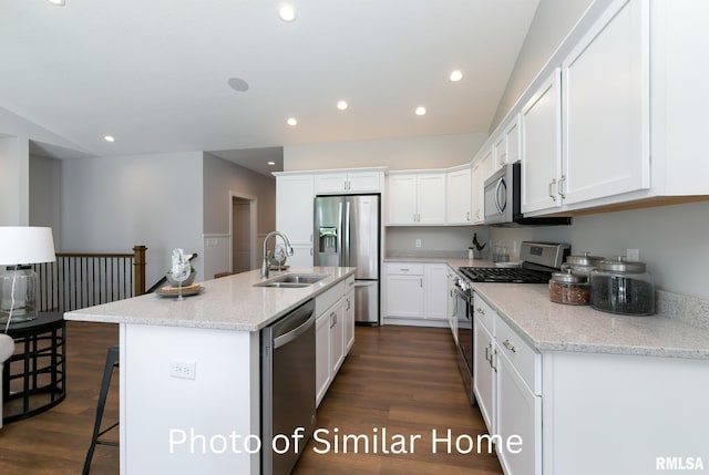 kitchen with sink, white cabinetry, light stone counters, a center island with sink, and stainless steel appliances