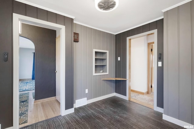 spare room featuring crown molding, dark wood-type flooring, and built in features