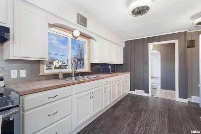 kitchen with appliances with stainless steel finishes, wood counters, white cabinetry, sink, and decorative backsplash