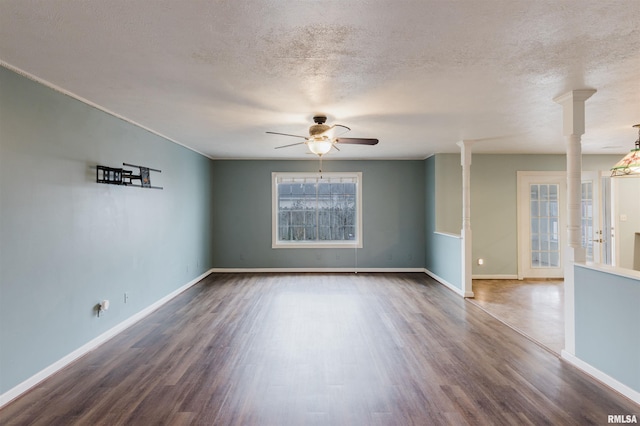 unfurnished room with ceiling fan, dark hardwood / wood-style floors, a textured ceiling, and ornate columns