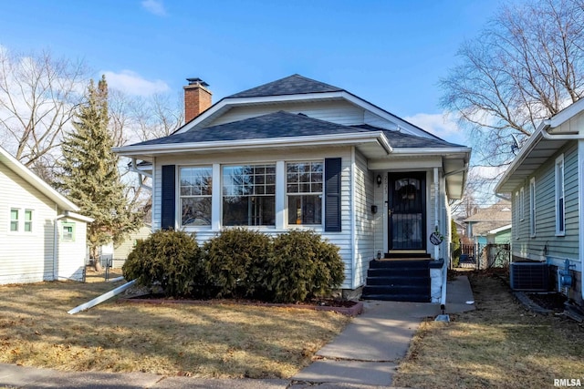 bungalow with a front yard and central air condition unit