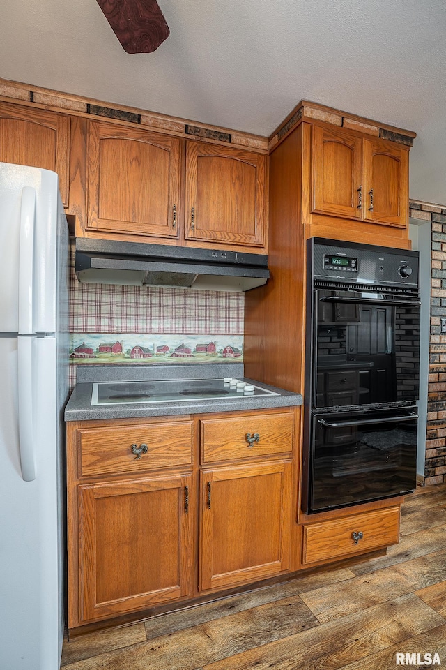 kitchen with dark hardwood / wood-style flooring, cooktop, double oven, and white fridge