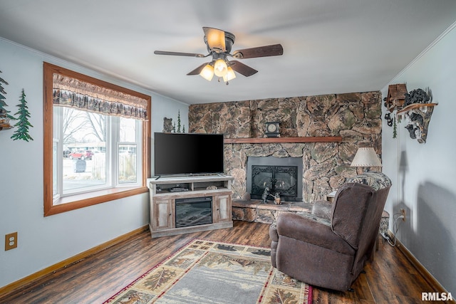 living room featuring dark wood-type flooring, ceiling fan, ornamental molding, and a fireplace