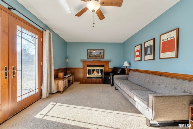 living room with light carpet, ceiling fan, and wood walls