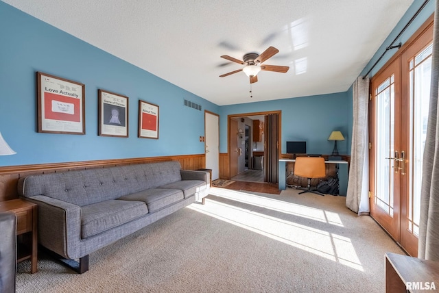 living room featuring light carpet, ceiling fan, french doors, and a textured ceiling