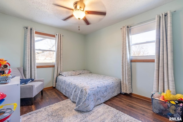 bedroom with ceiling fan, dark hardwood / wood-style floors, and a textured ceiling