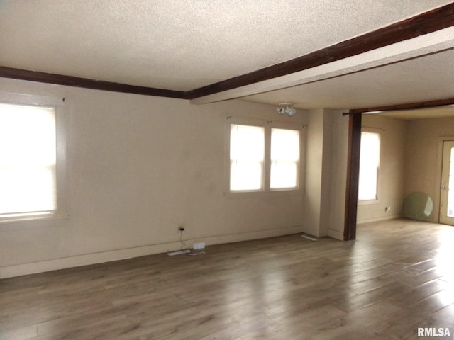 unfurnished room featuring beam ceiling, hardwood / wood-style floors, and a textured ceiling