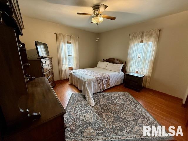 bedroom with dark wood-type flooring, ceiling fan, and multiple windows