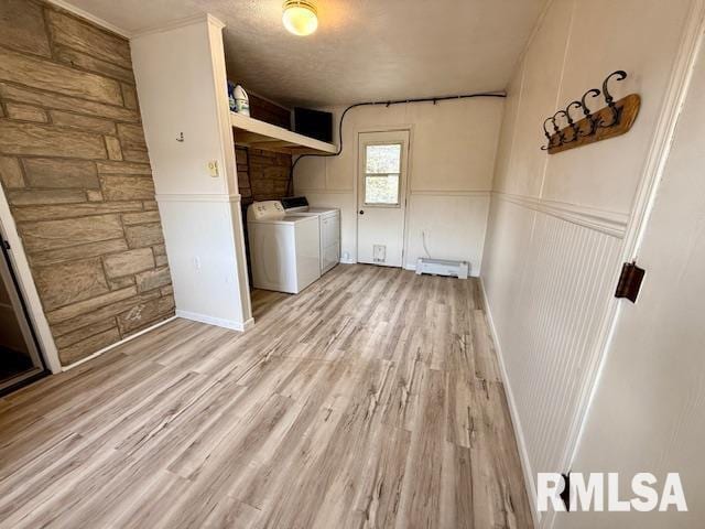 laundry area featuring a baseboard radiator, light hardwood / wood-style floors, and washing machine and dryer