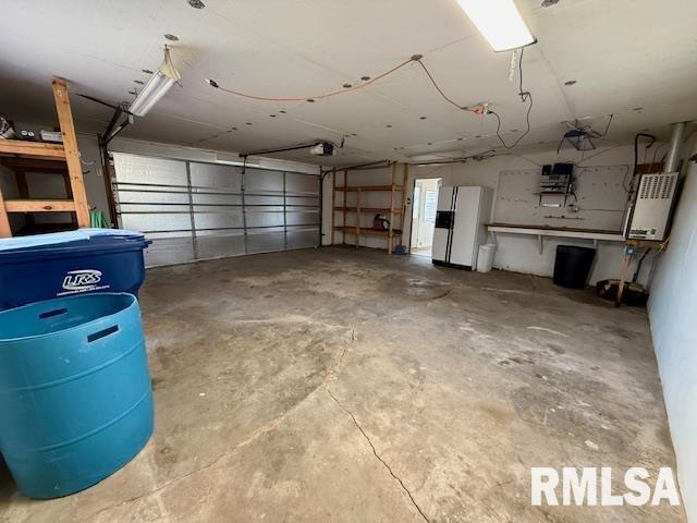 garage with a garage door opener and white fridge with ice dispenser