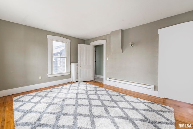 spare room featuring baseboard heating and hardwood / wood-style flooring