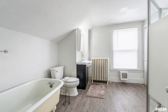 bathroom with lofted ceiling, radiator, hardwood / wood-style flooring, a bathing tub, and toilet