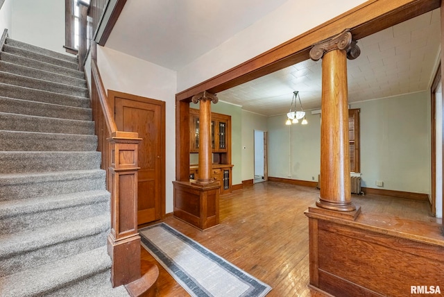 stairs with ornate columns, hardwood / wood-style flooring, and radiator