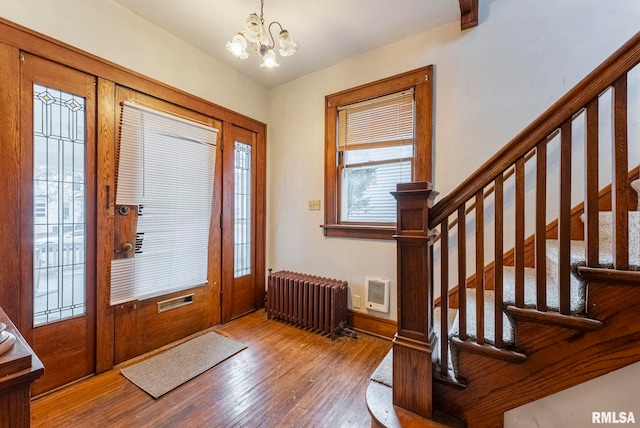 foyer entrance featuring an inviting chandelier, hardwood / wood-style flooring, and radiator heating unit