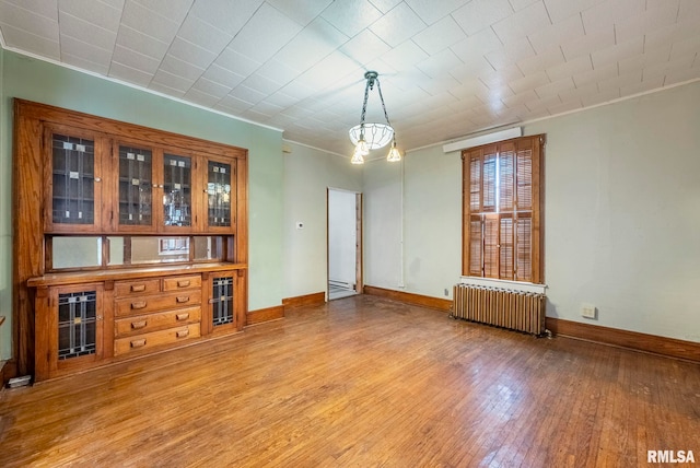 unfurnished dining area with ornamental molding, radiator, and light hardwood / wood-style flooring