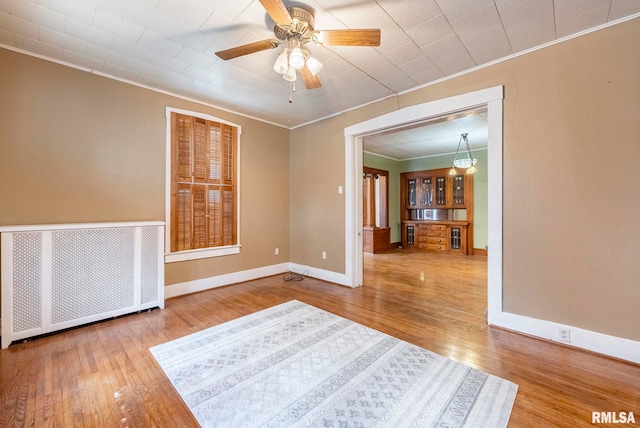 unfurnished room featuring hardwood / wood-style flooring, crown molding, and radiator