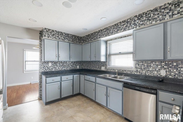 kitchen with sink, gray cabinets, stainless steel dishwasher, and plenty of natural light