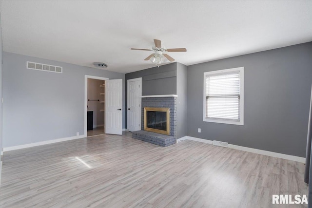 unfurnished living room featuring ceiling fan, a fireplace, and light wood-type flooring