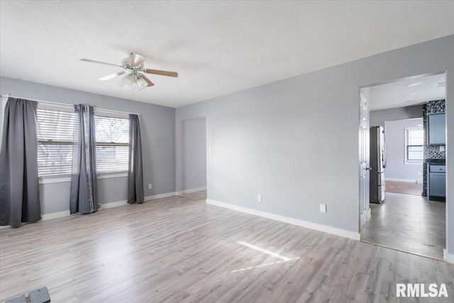 empty room featuring ceiling fan, a textured ceiling, and light wood-type flooring