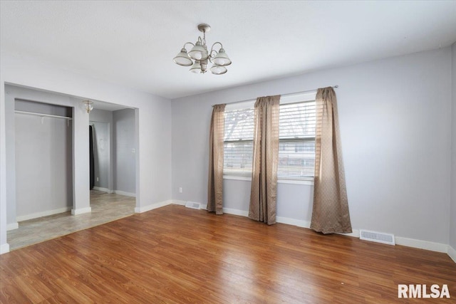 unfurnished room with wood-type flooring and a notable chandelier