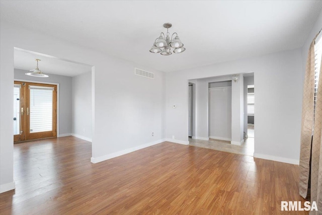 spare room featuring wood-type flooring and a notable chandelier