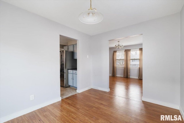 empty room with hardwood / wood-style floors and a notable chandelier