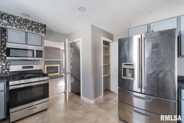 kitchen featuring a fireplace, stainless steel appliances, and a textured ceiling