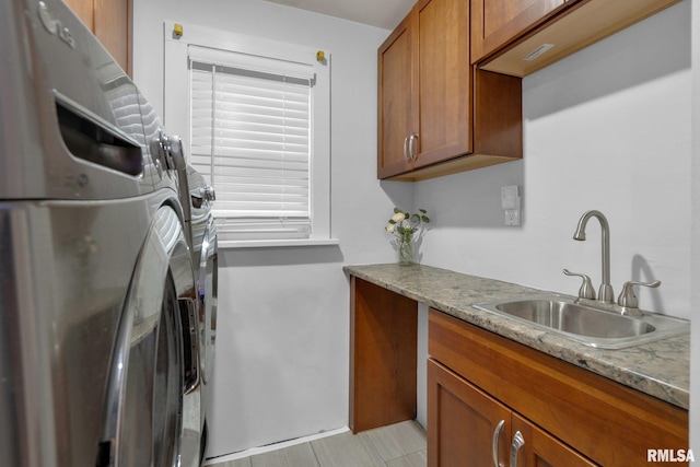 clothes washing area with sink, cabinets, and independent washer and dryer