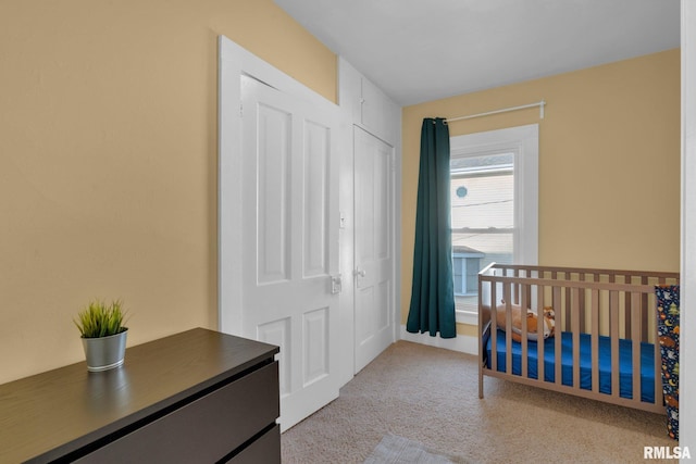 bedroom with a nursery area, light carpet, and a closet