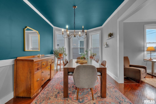 dining space with dark hardwood / wood-style flooring, a notable chandelier, and ornamental molding