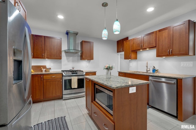 kitchen featuring sink, a center island, appliances with stainless steel finishes, pendant lighting, and wall chimney range hood