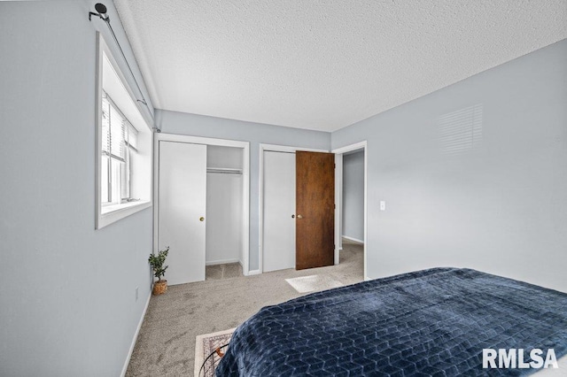 bedroom featuring carpet, two closets, and a textured ceiling