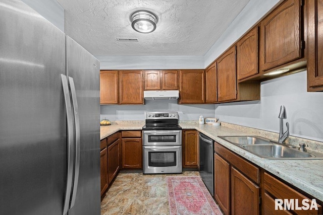 kitchen featuring appliances with stainless steel finishes, sink, and a textured ceiling